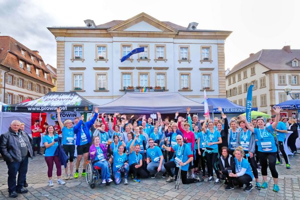 Mitarbeitende in Sportkleidung posieren bei einem Firmenevent für ein Gruppenfoto in der Stadt