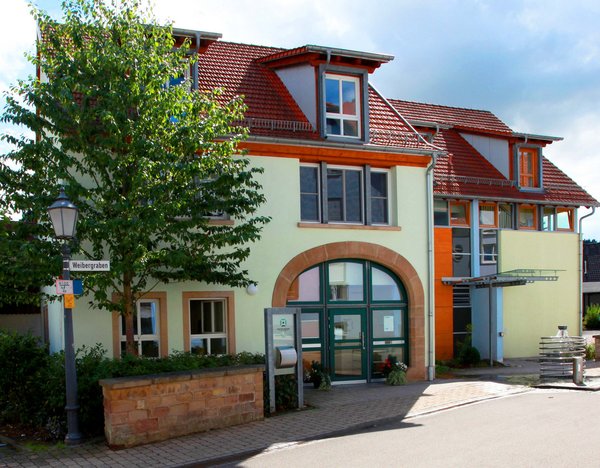 Blick auf eine Straße und den Eingangsbereich eines Gebäudes mit heller Fassade in Kusel